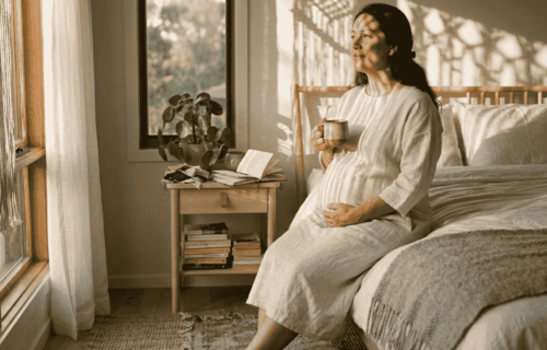 Mulher grávida depois dos 40 anos com mãos na barriga em luz natural quente