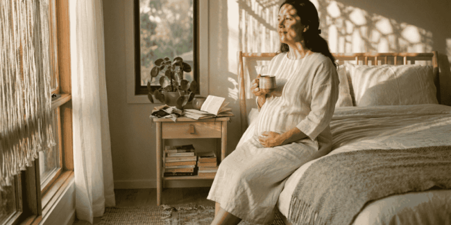 Mulher grávida depois dos 40 anos com mãos na barriga em luz natural quente